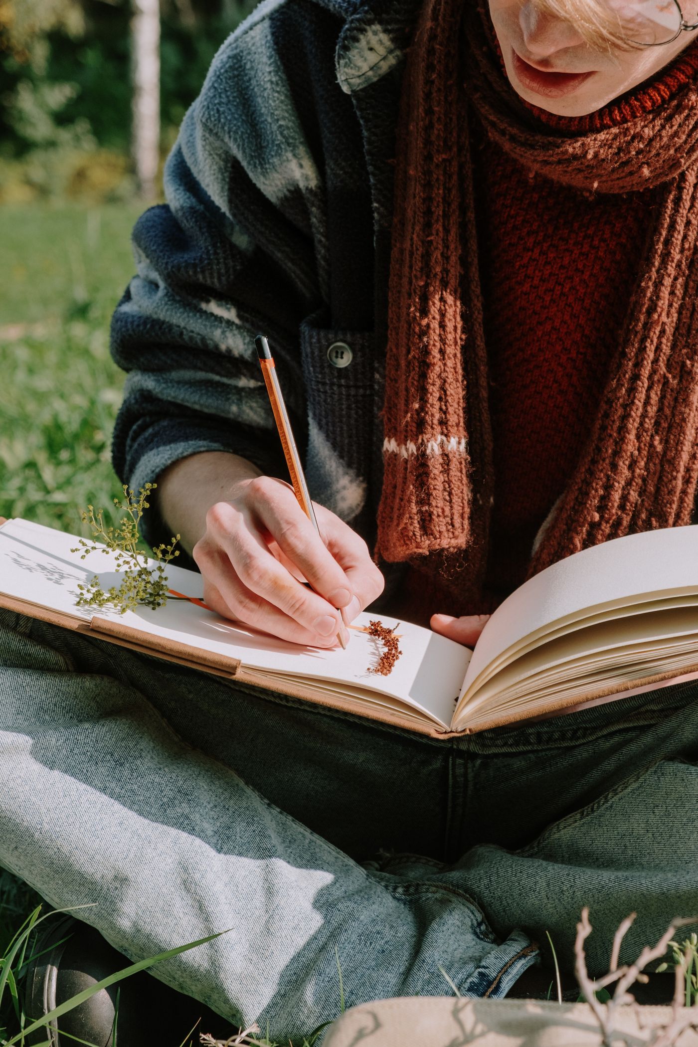 A person writing in a notebook outdoors