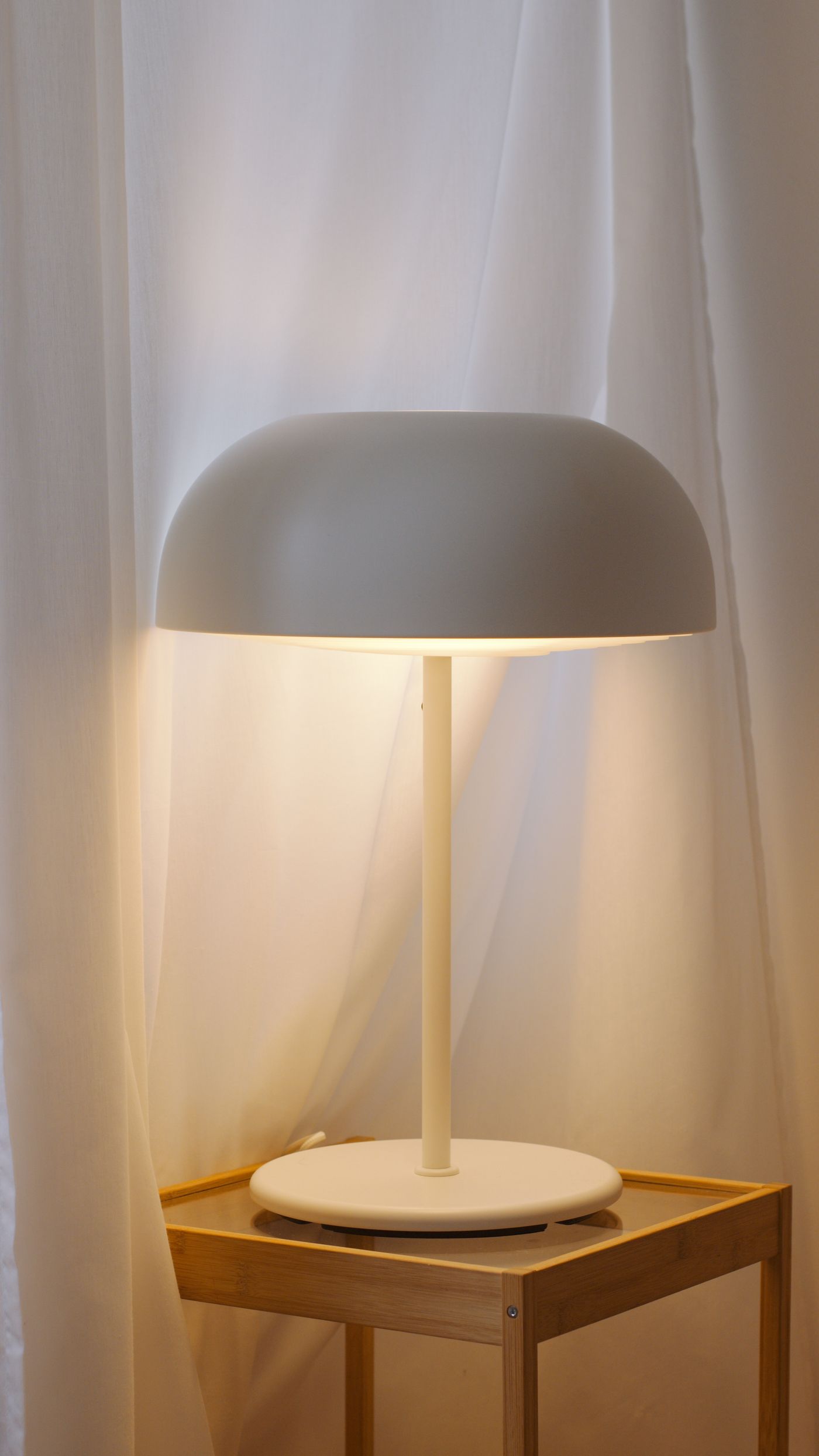 Table lamp glowing beside curtains